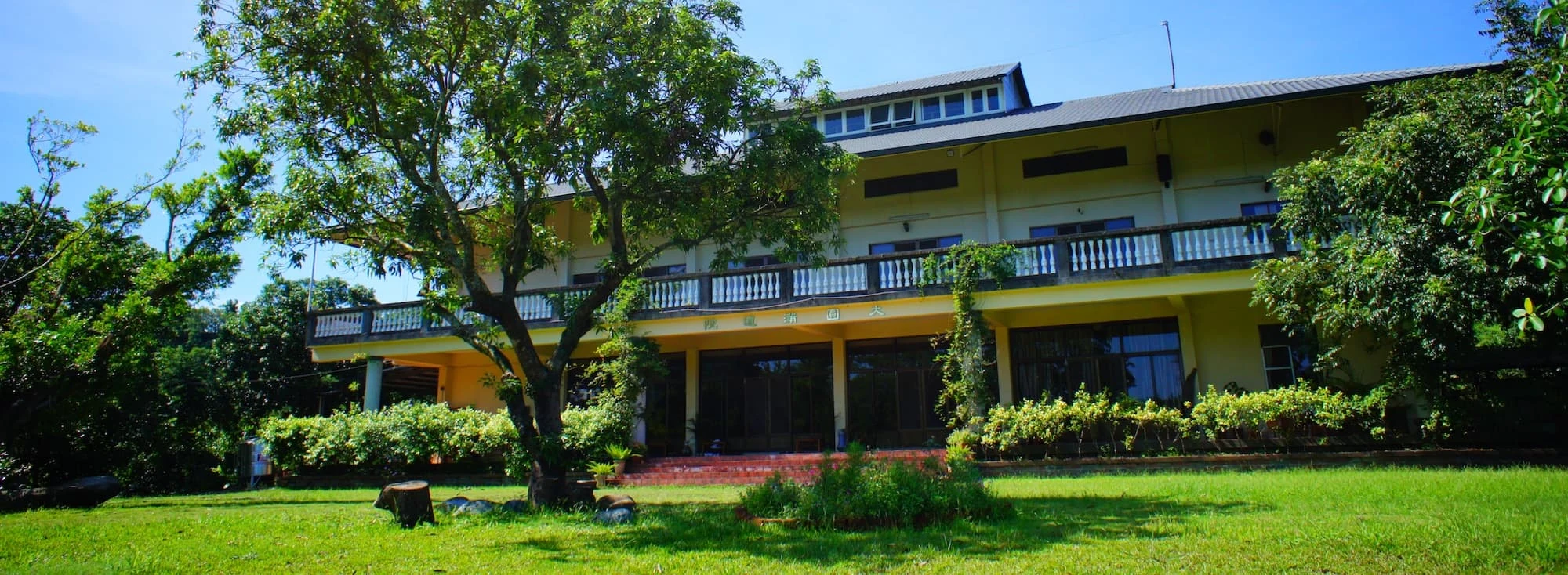 The main building beyond the lawn and mature trees