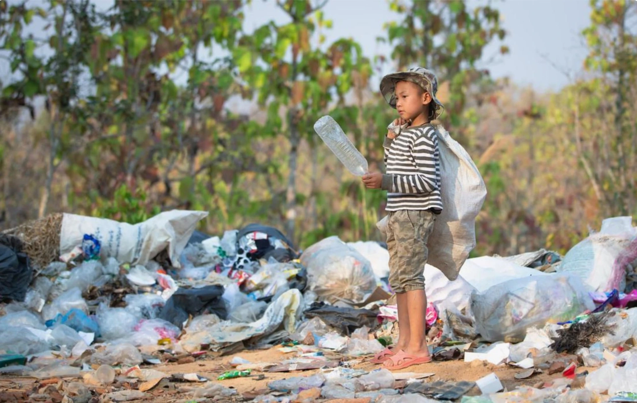 A boy carrying a collection sack among piles of discarded rubbish